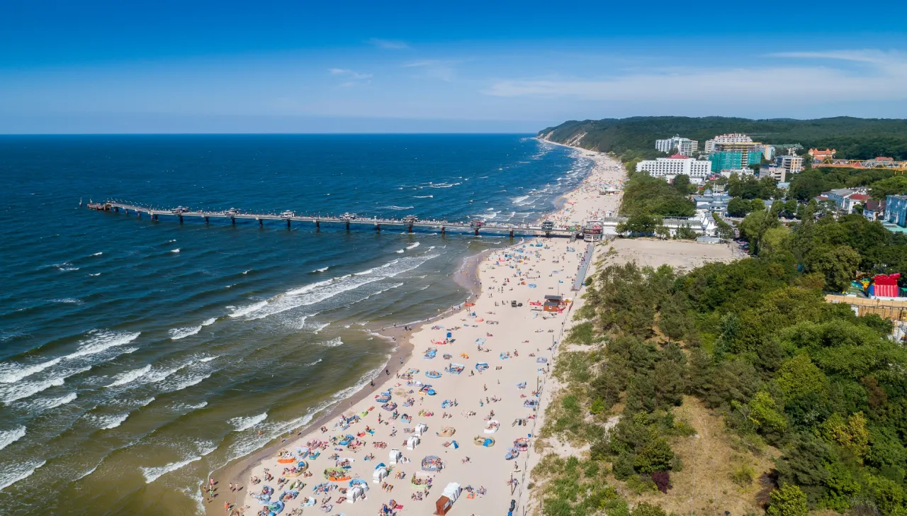 Widok na plażę i molo w Międzyzdrojach. Idealne miejsce, by zobaczyć, co zwiedzić w Międzyzdrojach, od plażowania po spacer po molo.