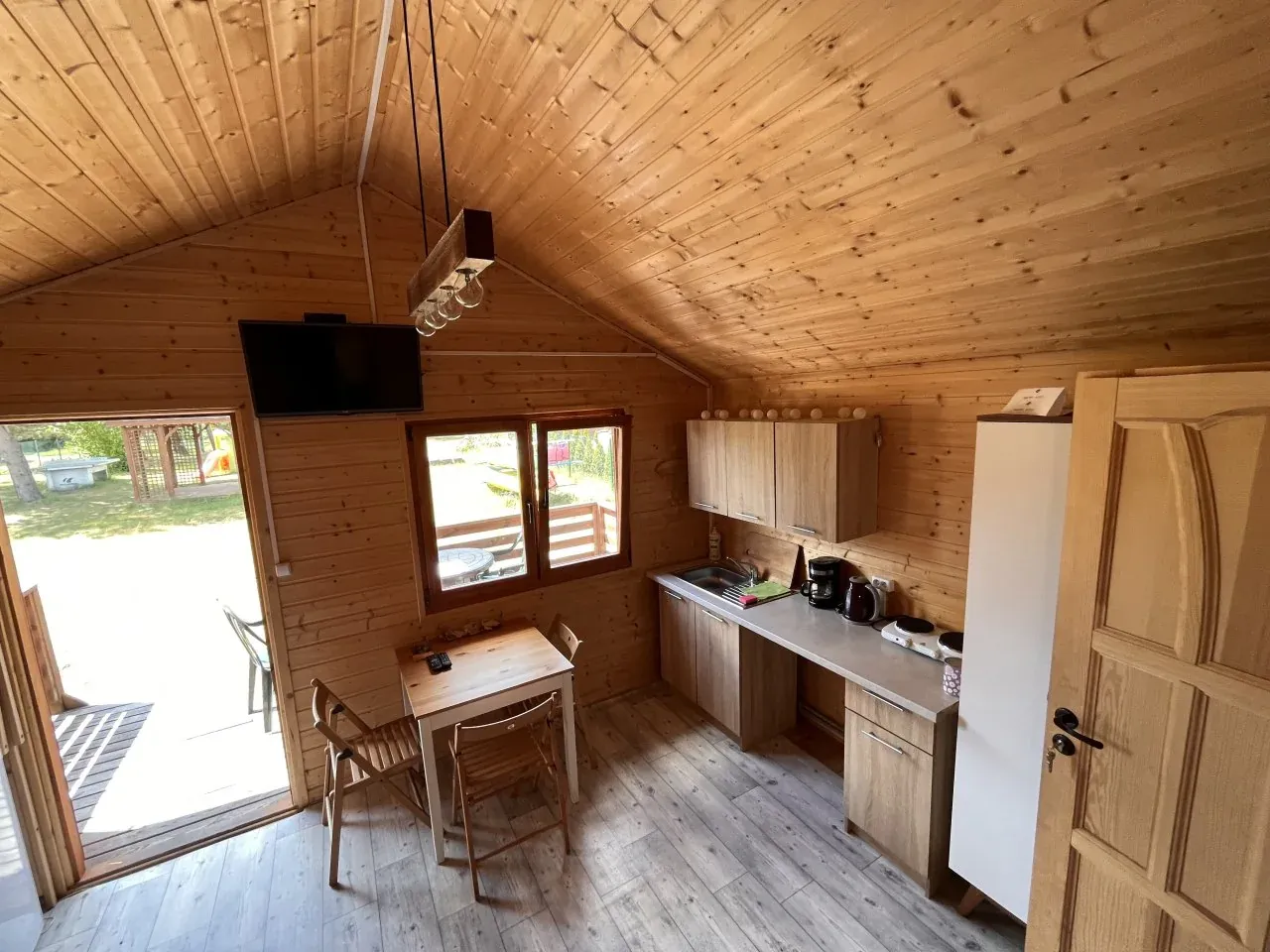 Drewniana chata z aneksem kuchennym i stołem, idealna na wypoczynek na pojezierzu fińskim.