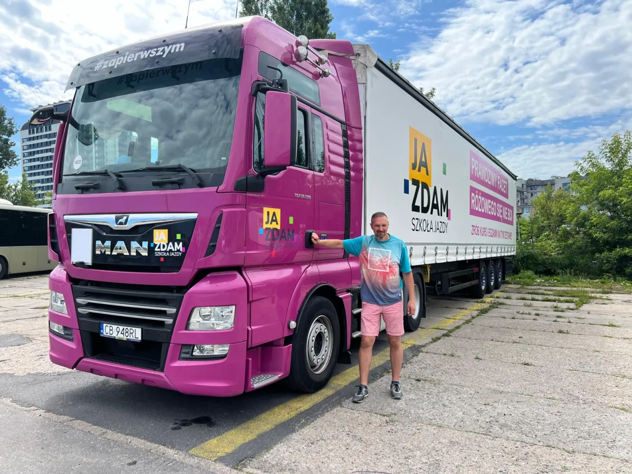 Mężczyzna obok różowej ciężarówki MAN. Szkoła jazdy 