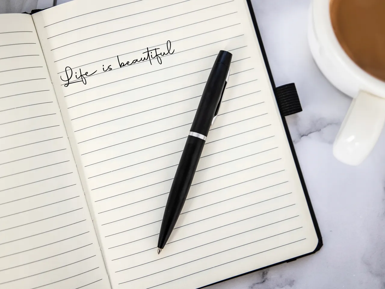 strona z zeszytu z ręcznymi zapiskami sprzedaży, obok leży długopis