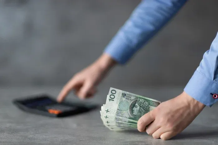 osoba licząca pieniądze na kalkulatorze w kontekście pożyczki