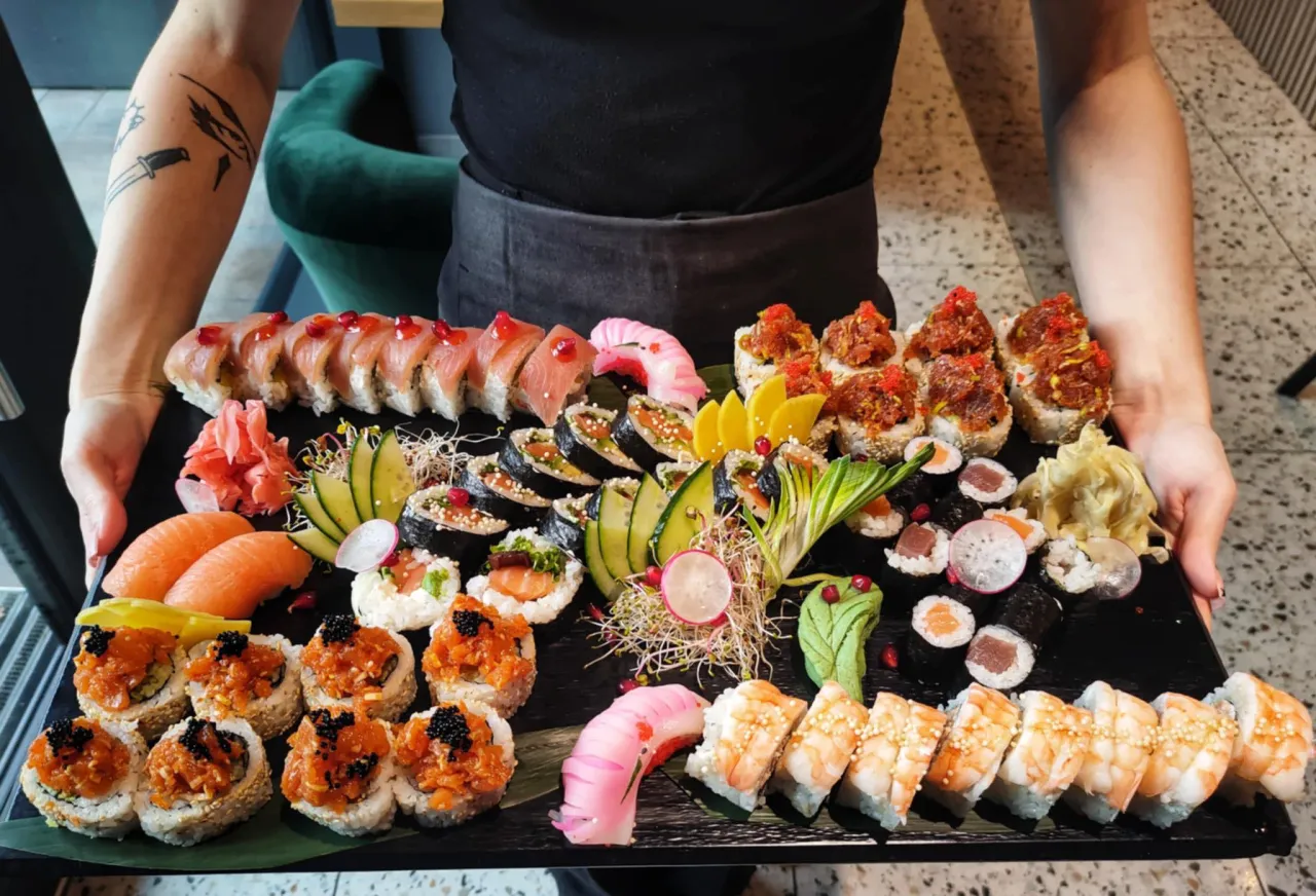 Bogata taca sushi z łososiem, krewetkami i r&oacute;żnymi rolkami. Idealna inspiracja, jak podawać sushi na elegancką okazję.