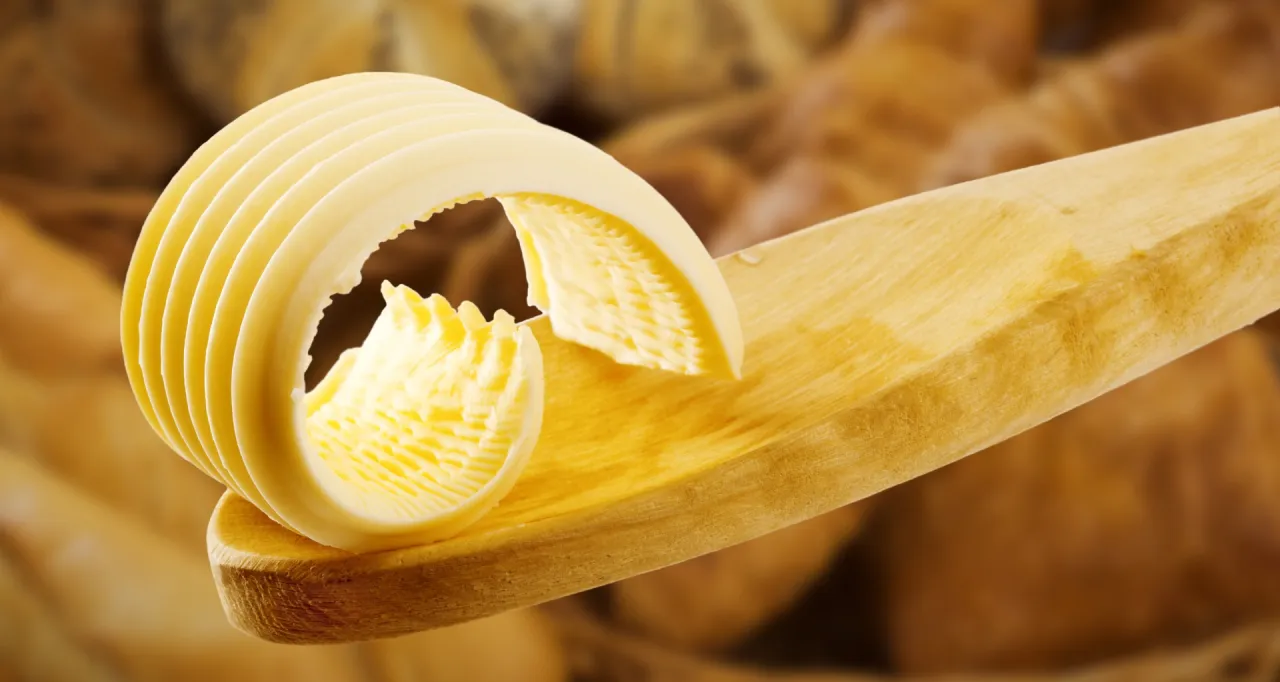 Zwijana kostka masła na drewnianej łyżce. Czy margaryna Kasi jest zdrowa? Pytanie o zdrowie tłuszczów.