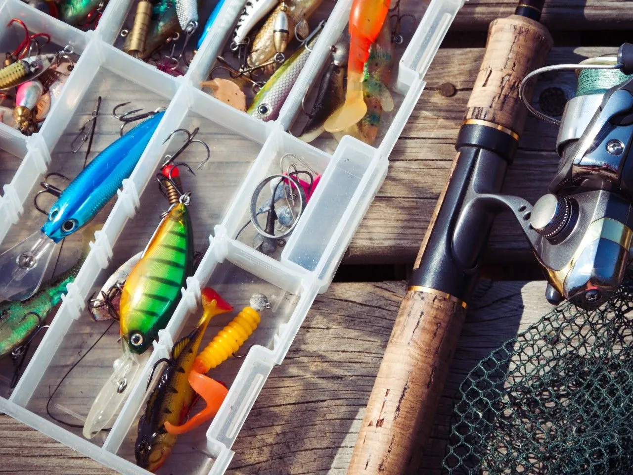 Przynęty na suma na spinning w pudełku, wędka i podbierak.