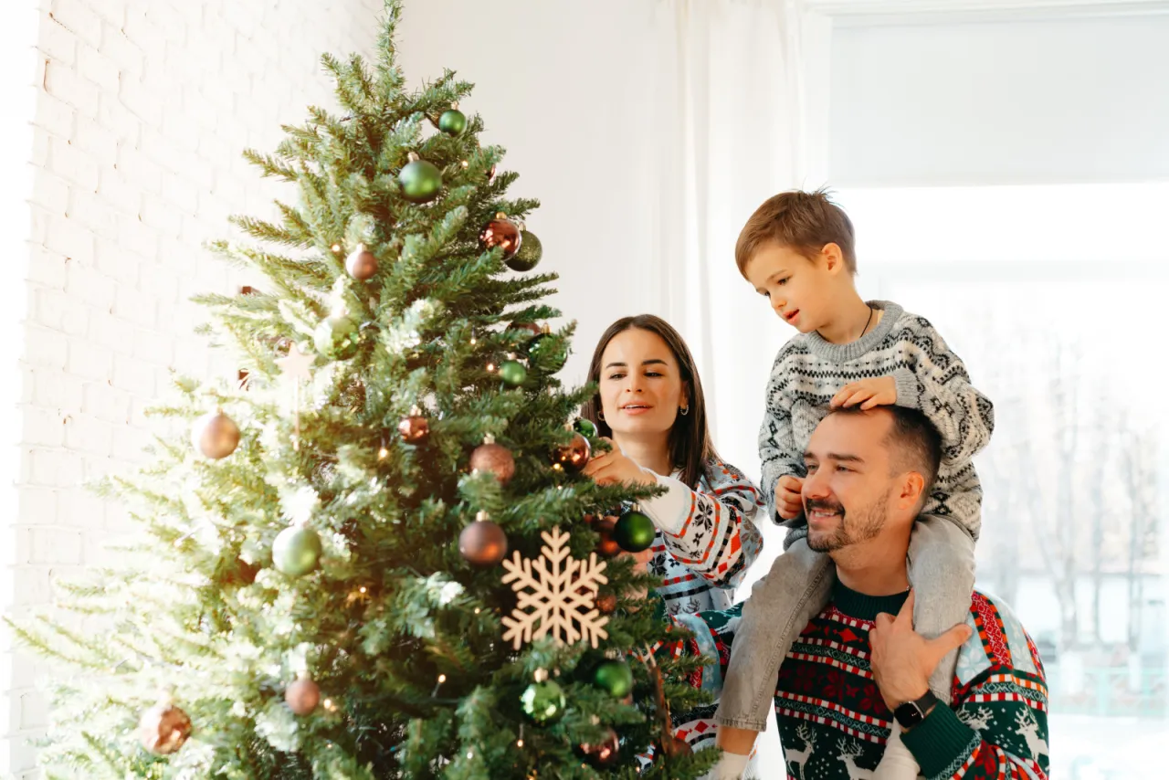 Rodzina stroi choinkę. Czas na świąteczne ozdoby, ale kiedy zdejmować ozdoby świąteczne?