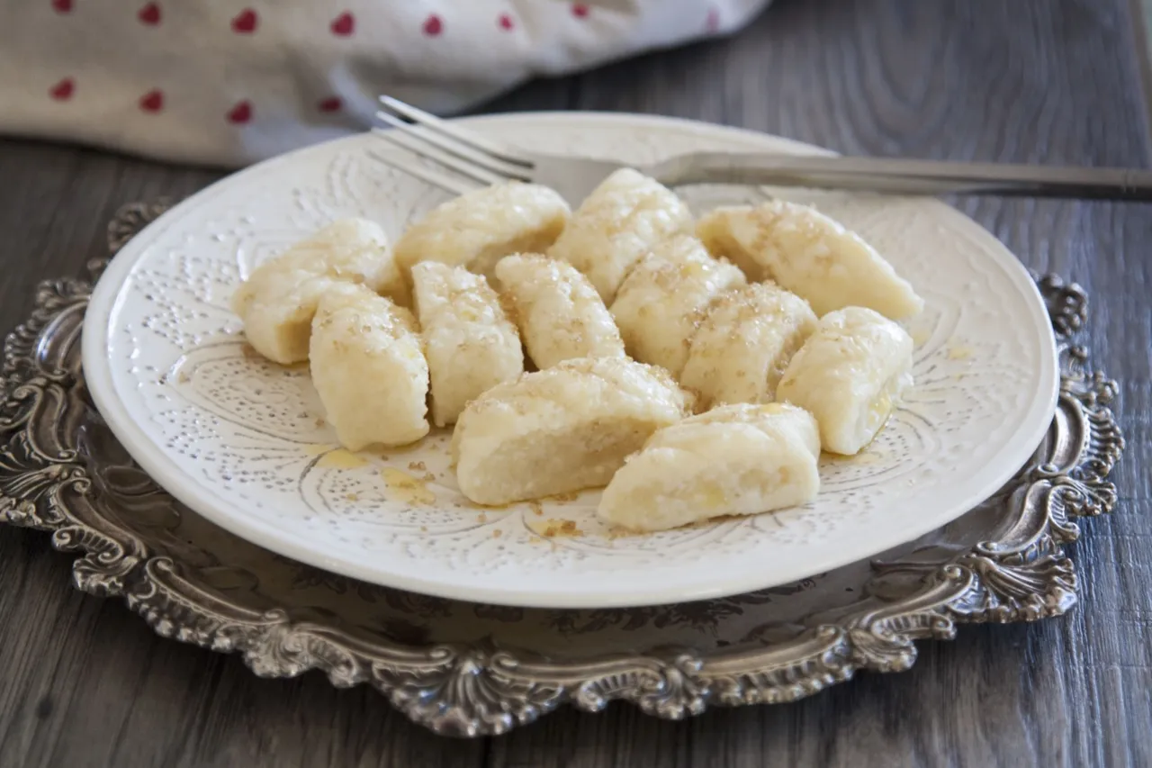 Pyszne pierogi leniwe posypane cukrem i polane masłem. Idealne na szybkie śniadanie lub deser.