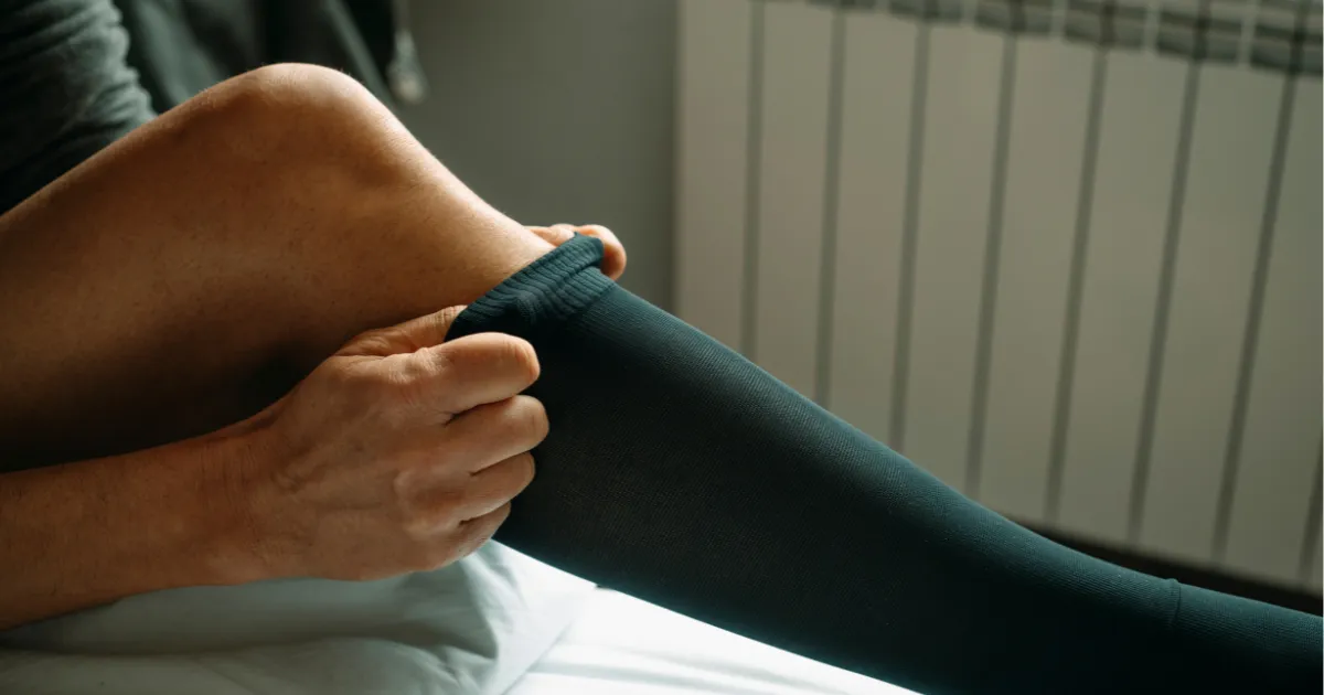 Osoba zakładająca pończochy uciskowe
