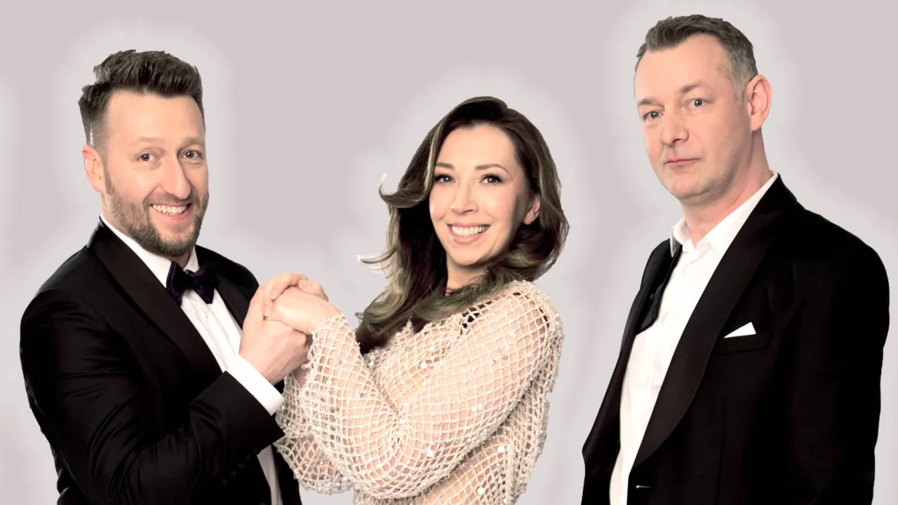 Kabaret Nowak: uśmiechnięty mężczyzna w muszce, kobieta w błyszczącej bluzce i mężczyzna w czarnym smokingu.