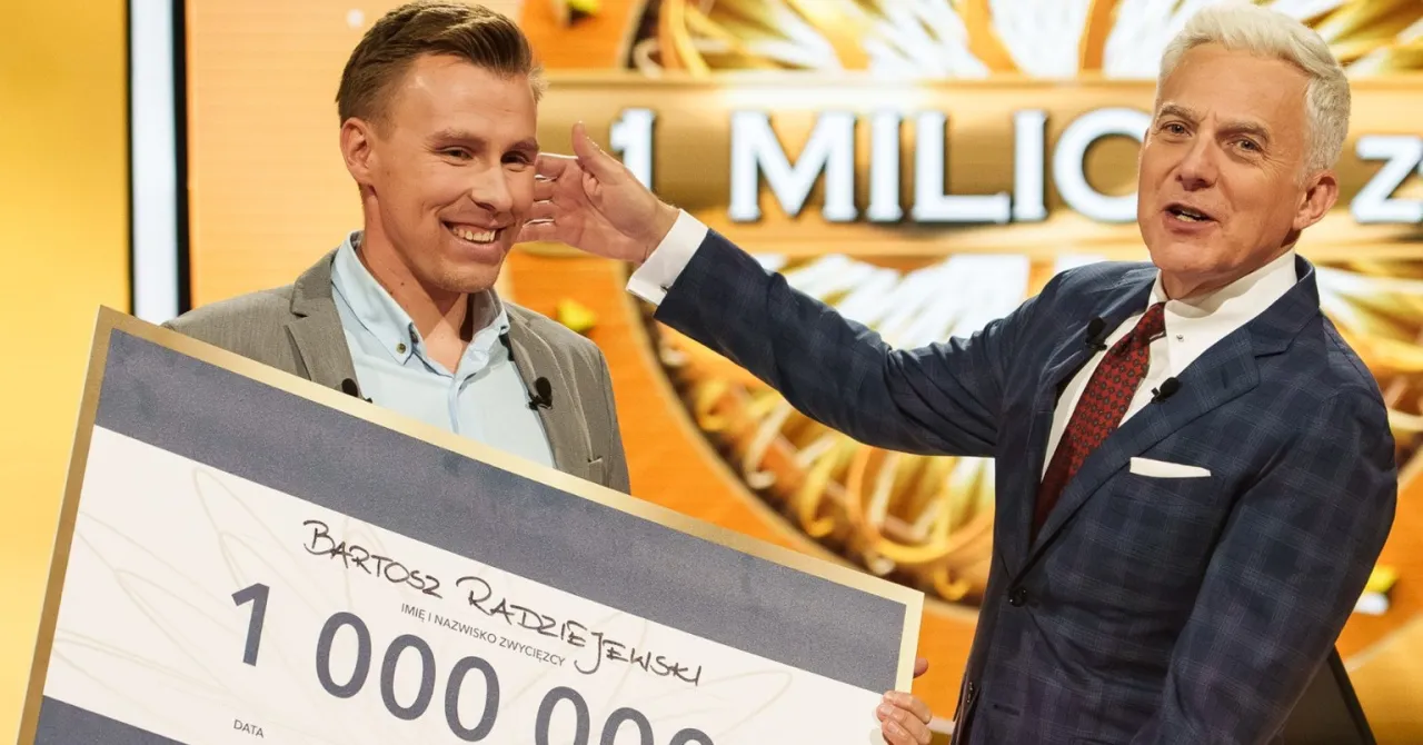 Bartosz Radziejewski, kt&oacute;ry wygrał milion w Milionerach, odbiera czek z nagrodą od prowadzącego.