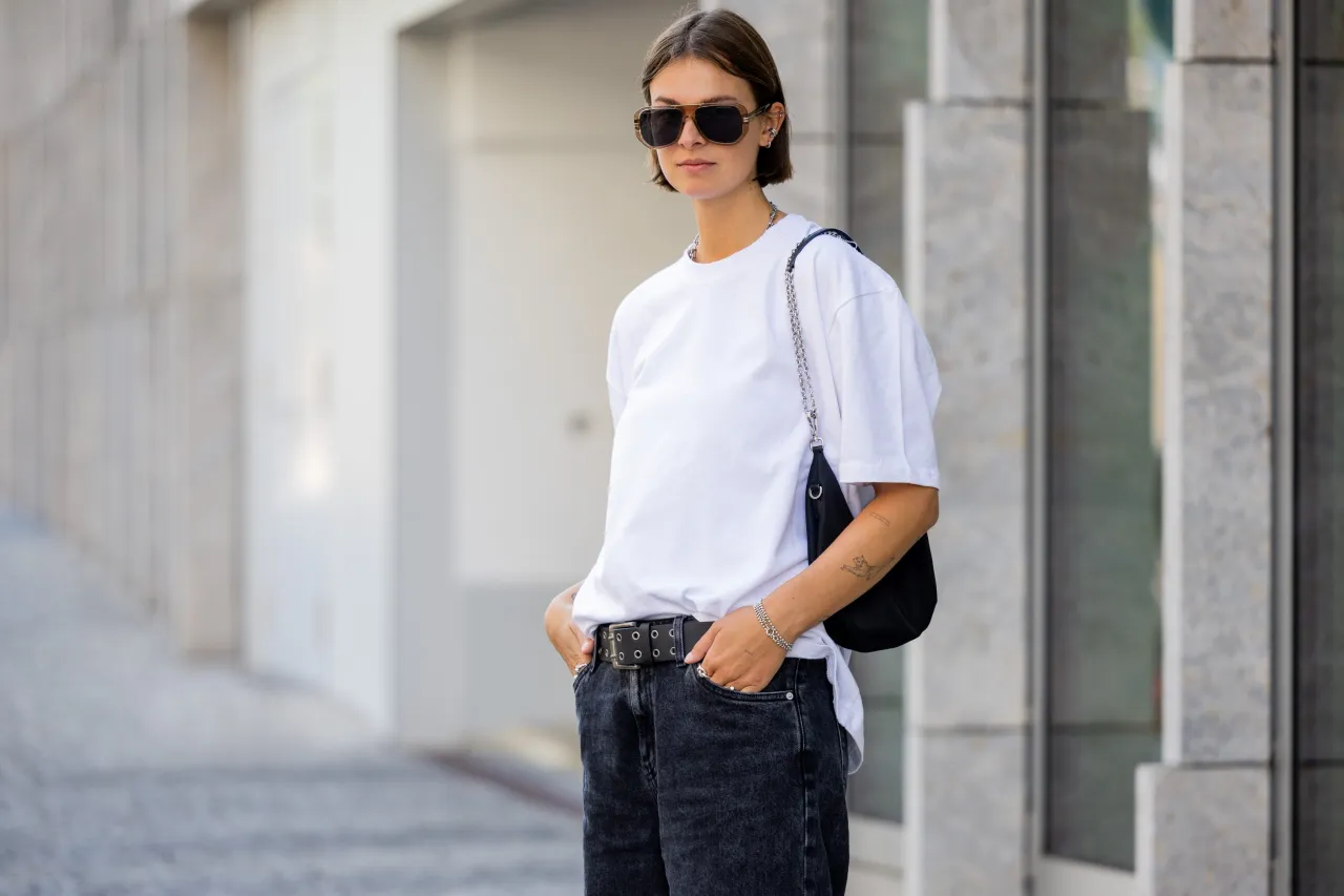 kobieta w jeansach i białym t-shircie z czarną listonoszką stylizacja street style