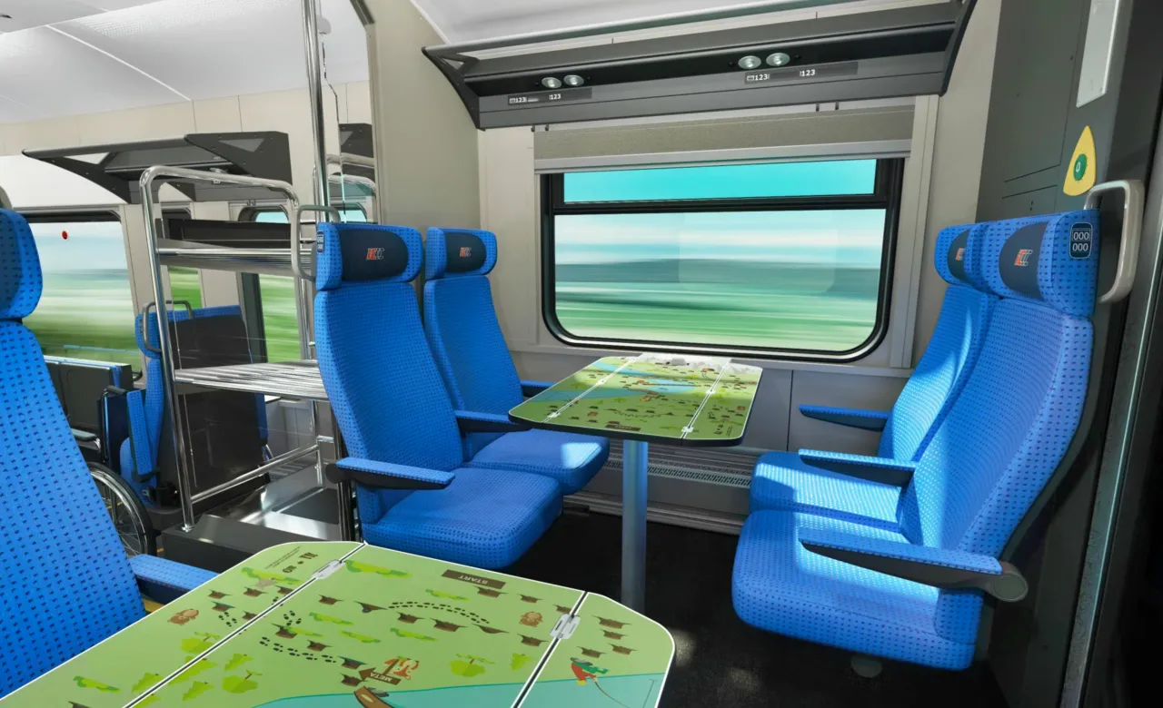 Wnętrze pociągu EIP z niebieskimi siedzeniami i stolikami. Widok przez okno sugeruje szybką podróż.