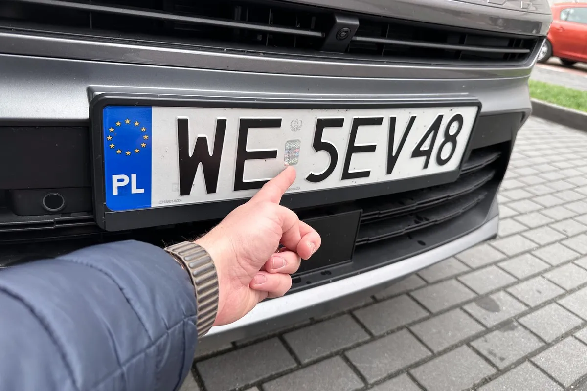 Palec wskazuje hologram na polskich tablicach rejestracyjnych. Czy można jeździć na niemieckich blachach? To pytanie nurtuje wielu kierowców.