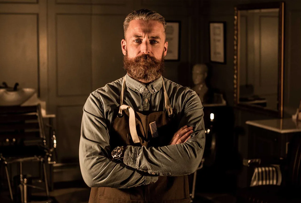 Barber strzygący brodę klienta z dobrze wyrośniętym zarostem