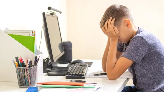 Uczeń przed komputerem smutny, negatywne skutki nauki zdalnej