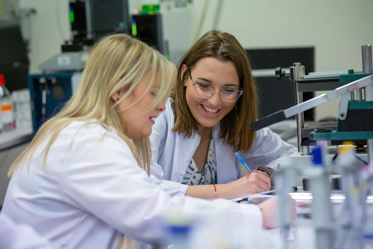 Dwie studentki w białych fartuchach pracują w laboratorium medycznym. To świetny przykład, jakie studia wybrać, by rozwijać pasję do nauki i medycyny.