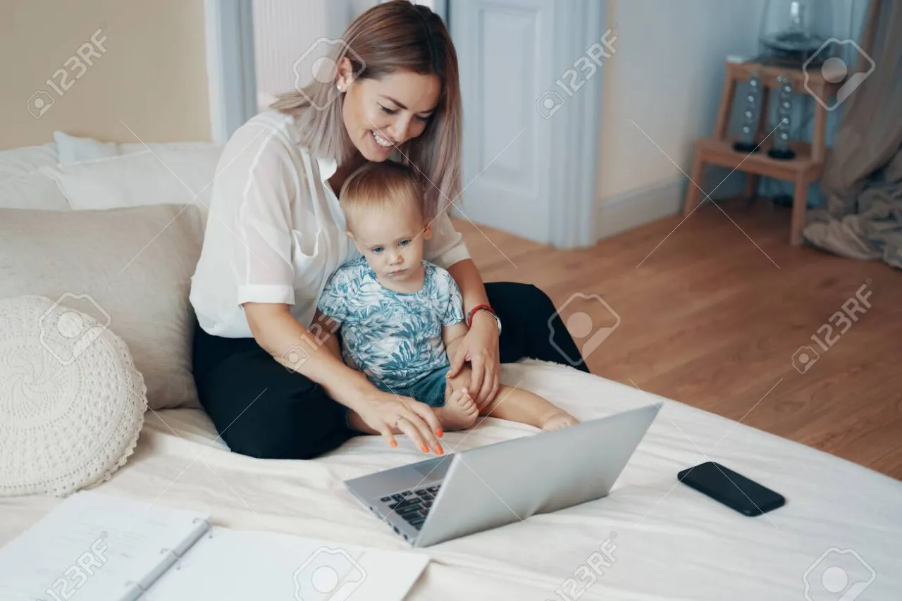 młoda matka z dzieckiem pracująca na laptopie w domu