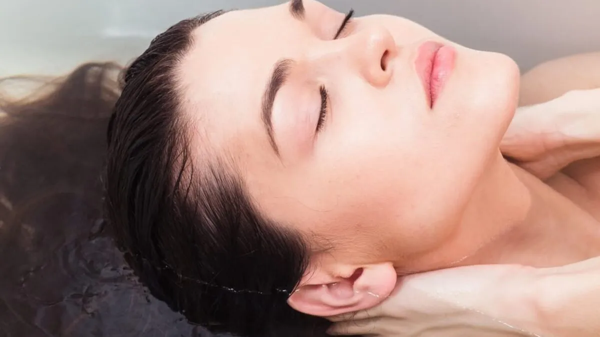 kobieta nakładająca płukankę na włosy nad miską