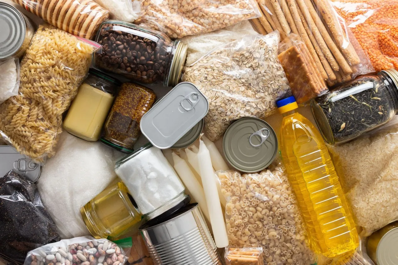 Zapasy żywności na kilka dni: makaron, ryż, płatki owsiane, soczewica, fasola, kawa, herbata, olej, cukier, konserwy, ciastka.