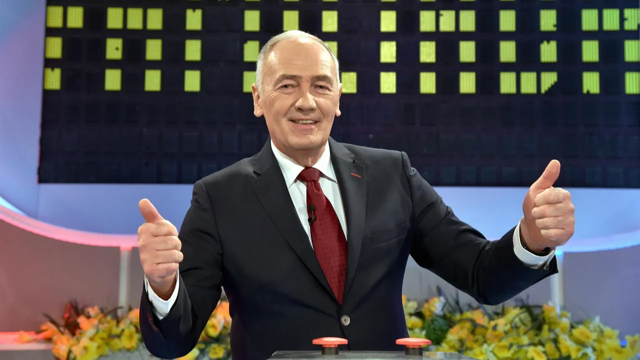 Uśmiechnięty prowadzący Familiady z kciukami w g&oacute;rze, gdy czegoś nie usłyszymy, pewnie pyta: 