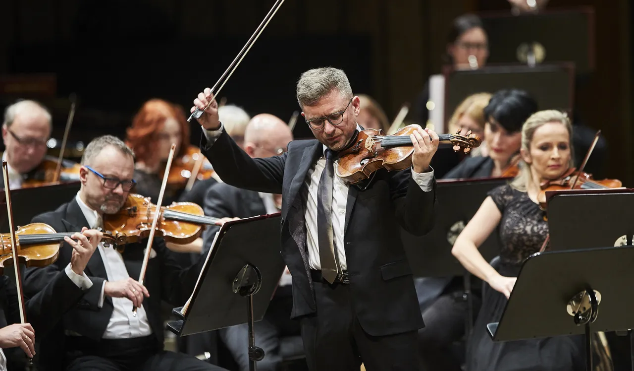 Dyrygent grający pierwsze skrzypce w orkiestrze, prowadzi muzyków z pasją.