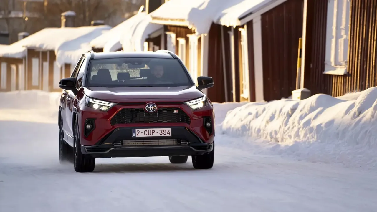Czerwona Toyota RAV4 Hybrid GR Sport jedzie po zaśnieżonej drodze. Zastanawiasz się, ile przejedzie hybryda Toyoty w takich warunkach?