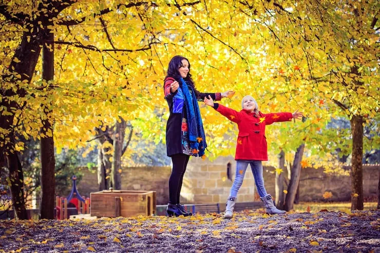 dwie przyjaciółki rozmawiające na ławce w parku, zamyślone, w tle jesienne liście
