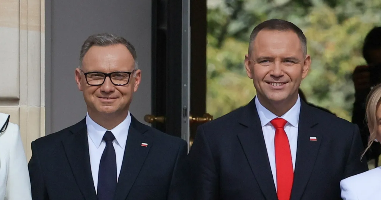 Andrzej Duda wzrost jest widoczny obok polityka z czerwoną muszką. Obaj panowie w garniturach uśmiechają się do obiektywu.