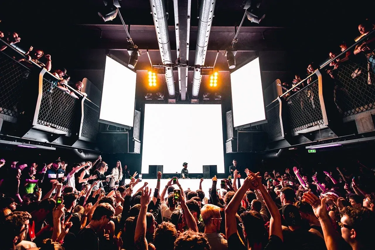 Tłum szaleje na koncercie, podnosząc ręce. DJ gra, a ekrany tworzą niesamowitą oprawę. Trudno zgadnąć, ile trwa koncert, ale zabawa jest przednia!