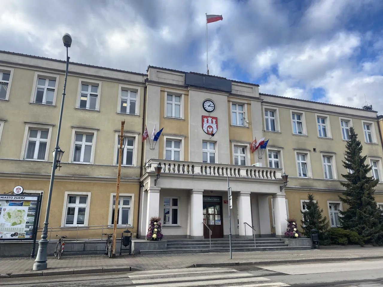 Urząd Miasta Zgierza z polską flagą. Zastanawiasz się, ile za śmieci w Zgierzu? Sprawdź informacje na tablicy ogłoszeń.