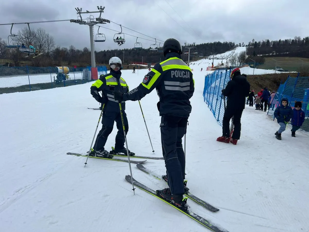 Policjanci na nartach patrolują czarne trasy narciarskie w Polsce. W tle kolejka linowa i inni narciarze.