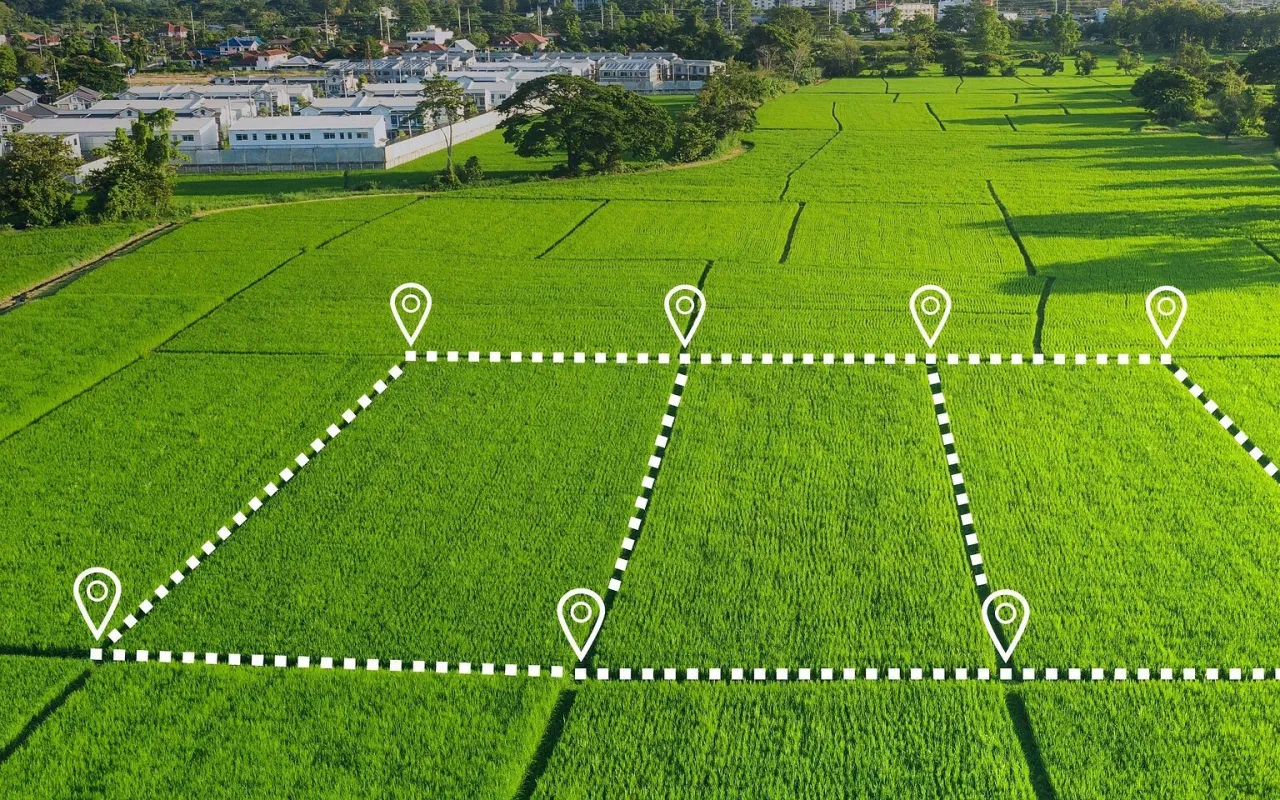 Zielona działka inwestycyjna, podzielona na mniejsze parcele białymi liniami i pinezkami. To potencjalny zysk!