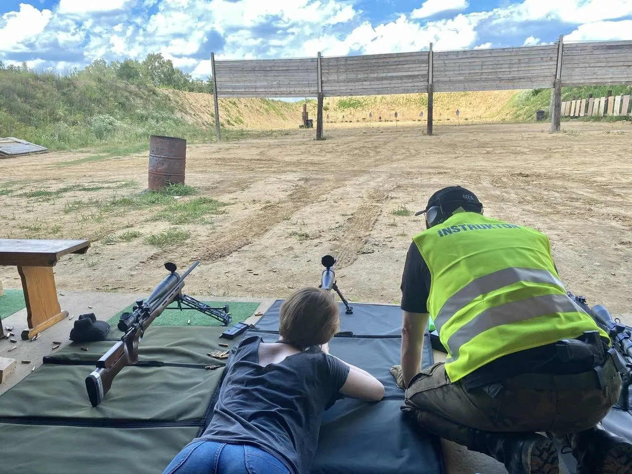 Osoba strzelająca pod okiem instruktora na strzelnicy