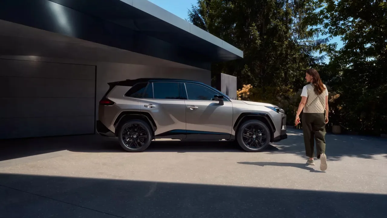 Kobieta idzie w stronę nowej hybrydy Toyoty. Zastanawiasz się, ile przejedzie hybryda Toyoty na jednym ładowaniu?