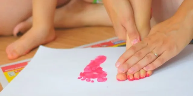 dziecko odrysowujące stopę na kartce papieru