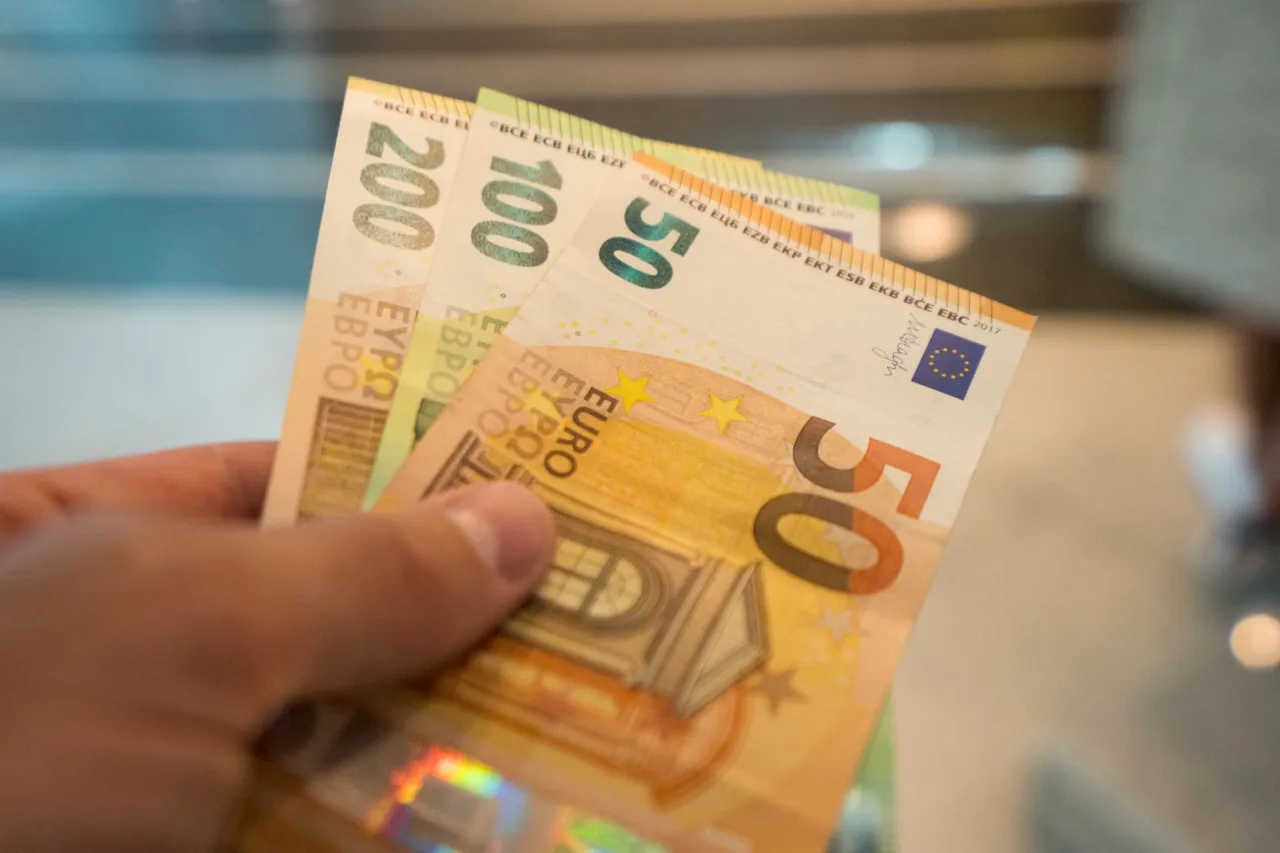 Dłoń trzyma banknoty 50, 100 i 200 euro. Od 2015 roku jaka waluta na Litwie to właśnie euro.