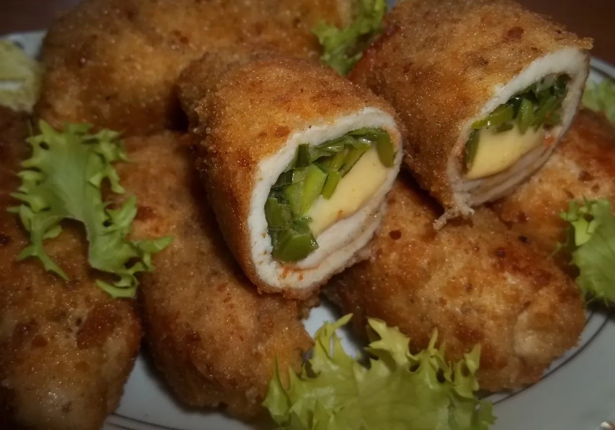 Złociste roladki drobiowe z serem i zielonym nadzieniem, podane z chrupiącą sałatą. Pyszne danie gotowe do spożycia.