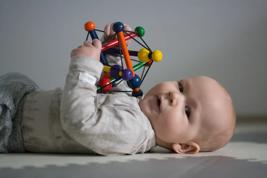 Szczęśliwe niemowlę bawi się zabawką 3 miesiące