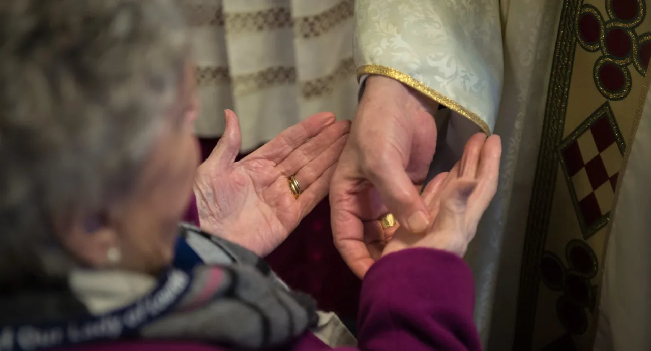 Kapłan udzielający namaszczenia chorych, osoba chora w łóżku, spokojna atmosfera
