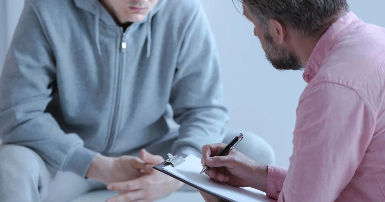 Lekarz rodzinny może przepisać leki na nerwicę. Rozmowa pacjenta z lekarzem, który notuje na kartce.