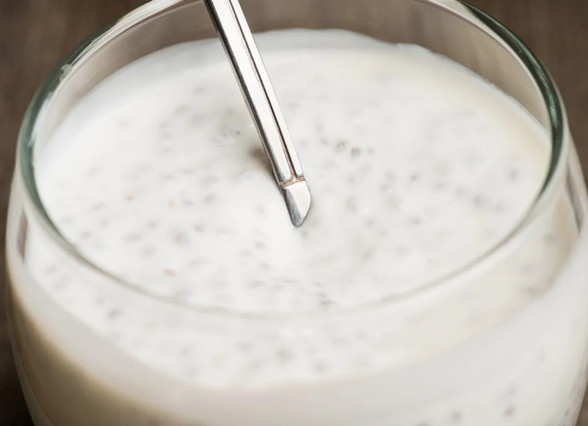 Mała łyżeczka kefiru w szklance, symbolizująca stopniowe wprowadzanie