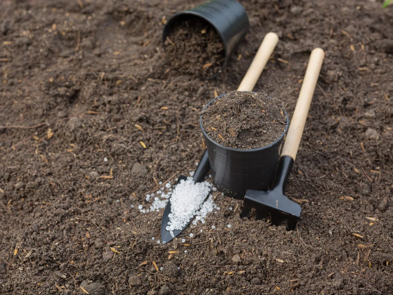 Narzędzia ogrodnicze i nawóz na ziemi, gotowe do użycia, by jak użyźnić glebę.