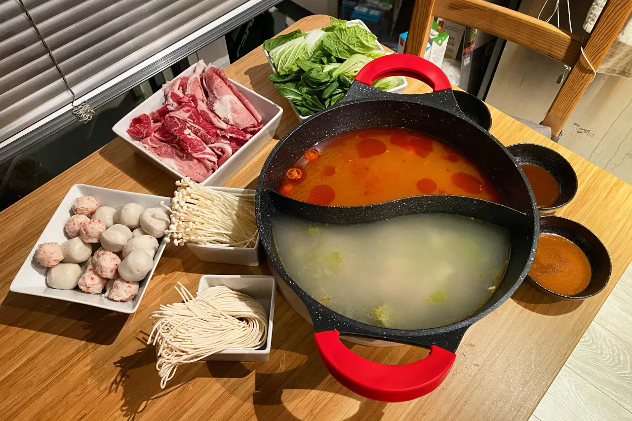 Składniki do hot pot: cienko pokrojone mięso, kulki rybne, grzyby enoki, makaron, warzywa i bulion w podzielonym garnku. Idealny przepis na hot pot!