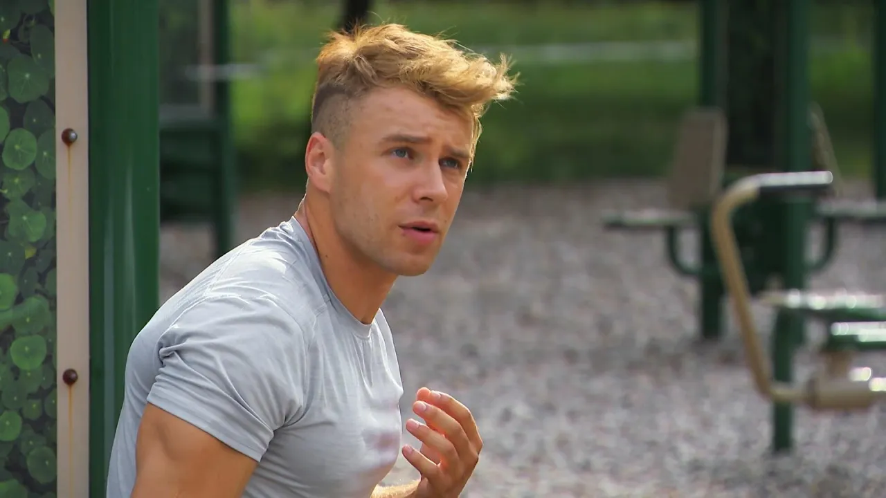 Młody mężczyzna z blond włosami, w szarym t-shircie, siedzi na siłowni plenerowej. Czy Skolim gra jeszcze w barwach szczęścia?