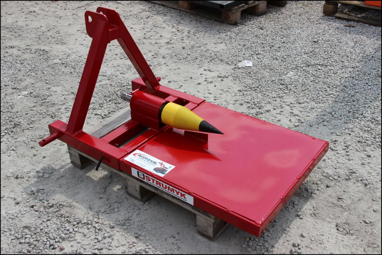 Czerwona łuparka do drewna do ciągnika z żółtym stożkiem, gotowa do pracy w gospodarstwie.