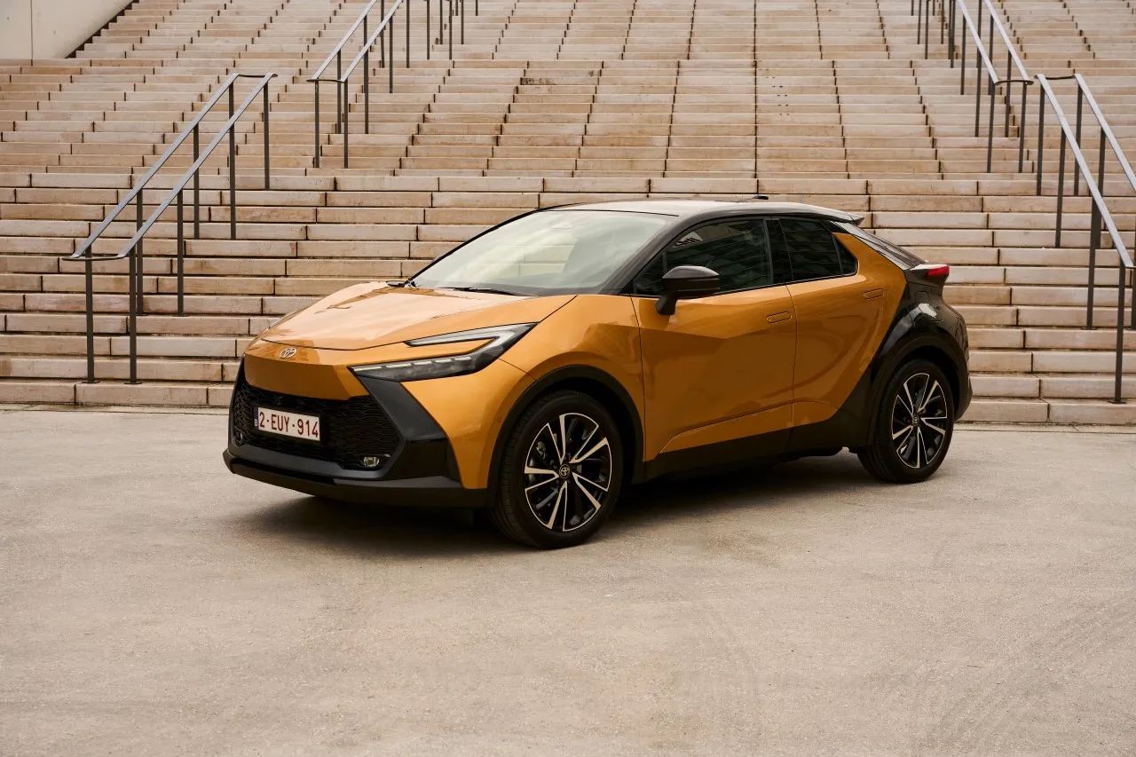Złoty Toyota C-HR hybryda czy benzyna? Stylowy crossover z czarnymi akcentami na tle schod&oacute;w.
