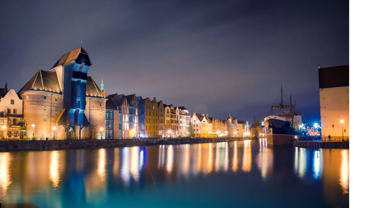 Nocny widok na Motławę w Gdańsku, z Żurawiem i zabytkową zabudową. To miejsce, co warto zobaczyć na Pomorzu, zachwyca o każdej porze.