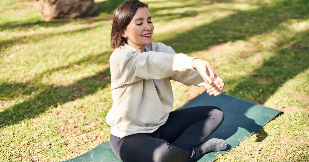 Osoba rozciągająca się z uśmiechem, pokazująca elastyczność