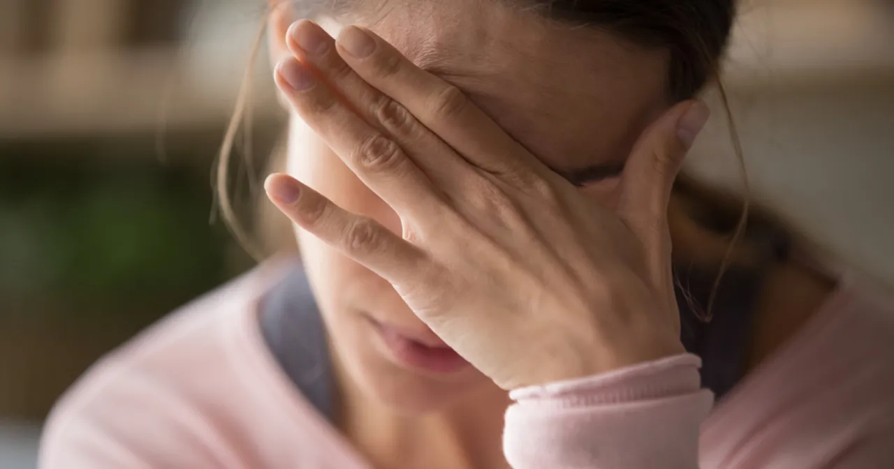 Kobieta z ręką na czole, cierpiąca na b&oacute;l głowy przy zmianie pogody. Szuka ulgi i sposob&oacute;w, co na b&oacute;l głowy przy zmianie pogody.