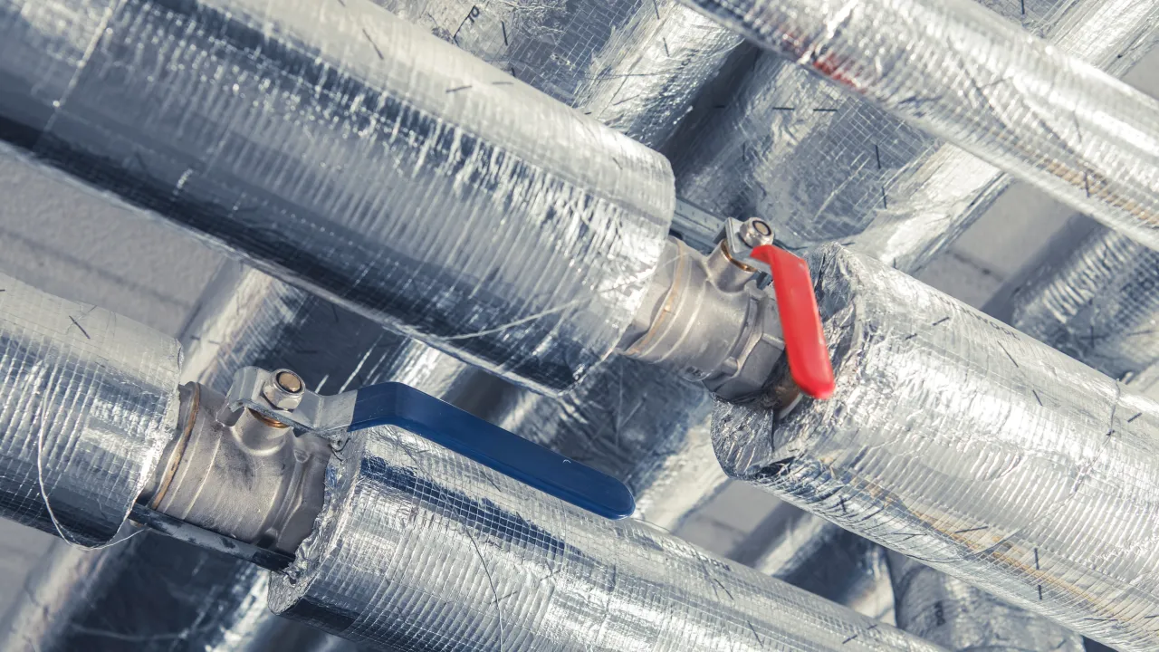 Izolowane rury z zaworami, pokazujące jak ocieplić rury z wodą na zewnątrz, by zapobiec zamarzaniu.