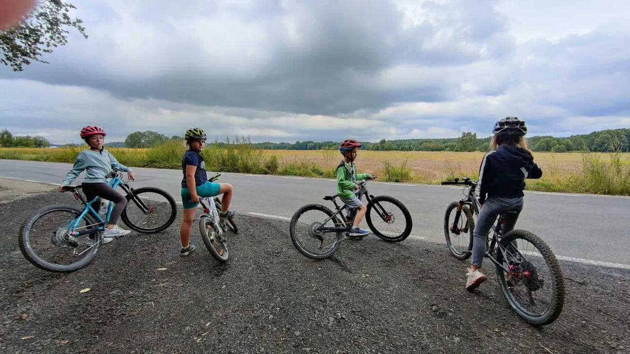 Dzieci na rowerach, szukają idealnego roweru na 140 cm wzrostu. W tle pole i chmury.